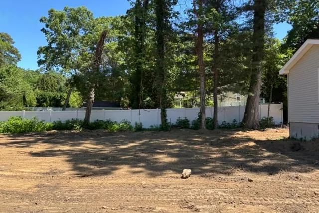Site photograph of the empty rear lot looking toward the boundary fence and mature trees
